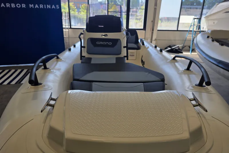 Slide: The Image of 2027 Grand Inflatables G420 boat interior, showcasing seating and controls in a showroom. - 4