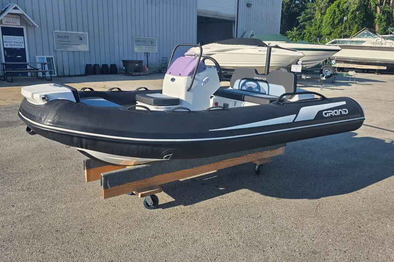 Slide: The Image of 2027 Grand Inflatables G380N boat displayed outdoors on a wooden stand. - 5