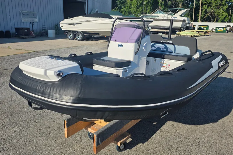 Slide: The Image of 2027 Grand Inflatables G380N boat displayed outdoors on a wooden stand. - 4