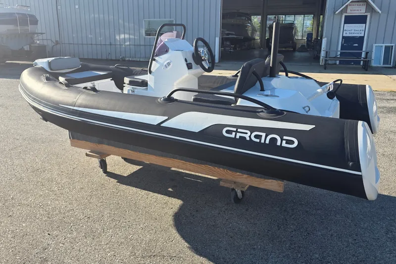 Slide: The Image of 2027 Grand Inflatables G380N boat displayed outdoors on a wooden stand. - 6