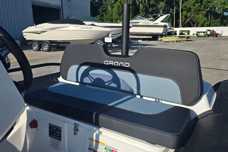 Slide: The Image of 2027 Grand Inflatables G380N boat seat with logo, parked near other boats. - 10
