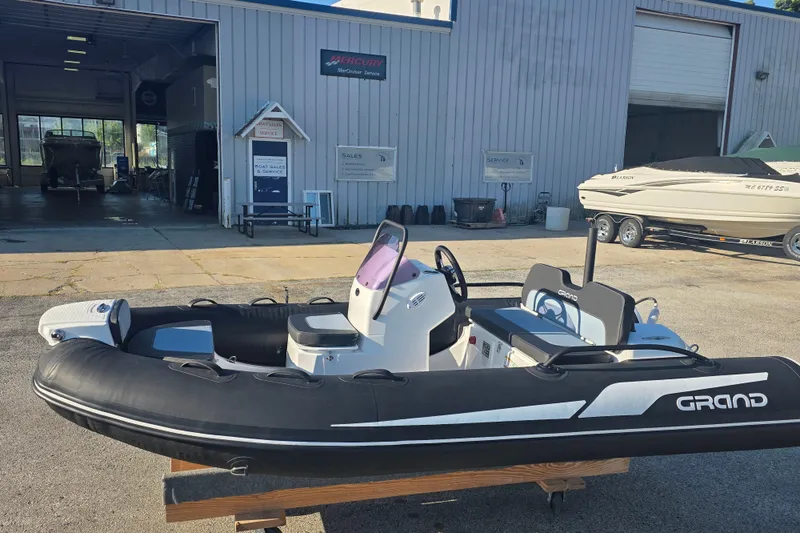 Slide: The Image of 2027 Grand Inflatables G380N boat displayed outside a marine service center. - 12