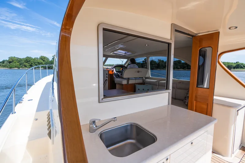 Slide: The Image of 2017 Palm Beach Motor Yachts PB42 interior with sink, overlooking serene waters and lush greenery. - 12