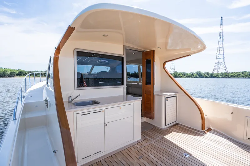 Slide: The Image of 2017 Palm Beach Motor Yachts PB42, elegant deck view with sink, wooden accents, and scenic water backdrop. - 10