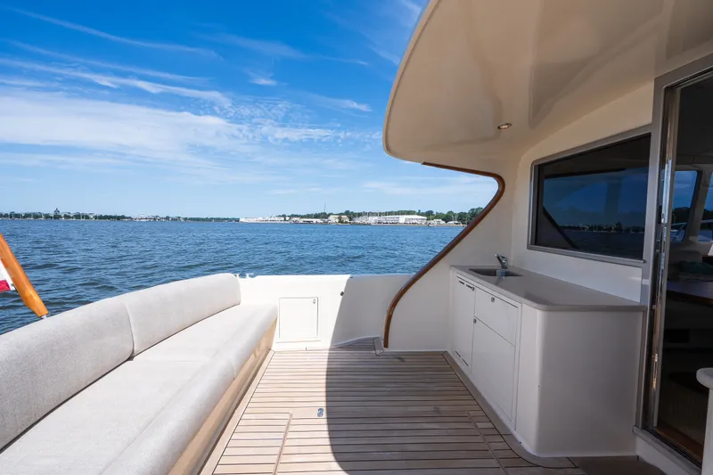 Slide: The Image of 2017 Palm Beach Motor Yachts PB42 deck with seating, overlooking serene waters and blue sky. - 17