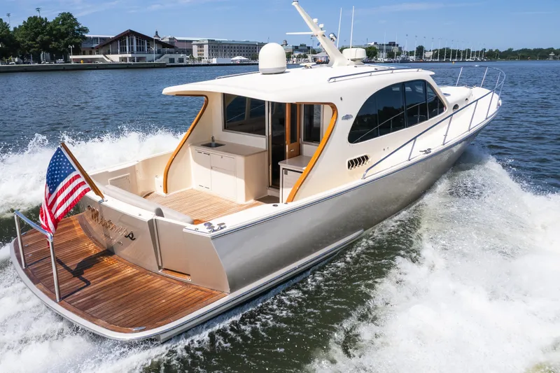 Slide: The Image of The 2017 Palm Beach Motor Yachts PB42 cruising on calm waters with an American flag at the stern. - 1
