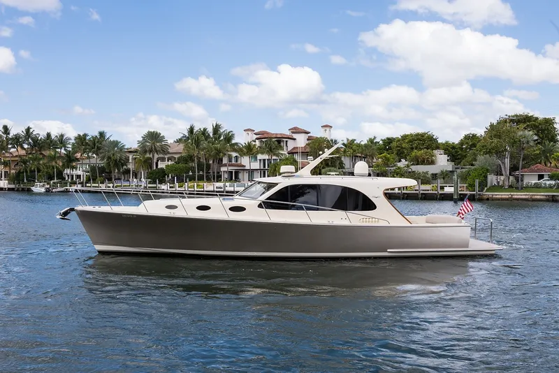 The Image of 2017 Palm Beach Motor Yachts PB42 cruising on a scenic waterway with luxury homes in the background. - 0