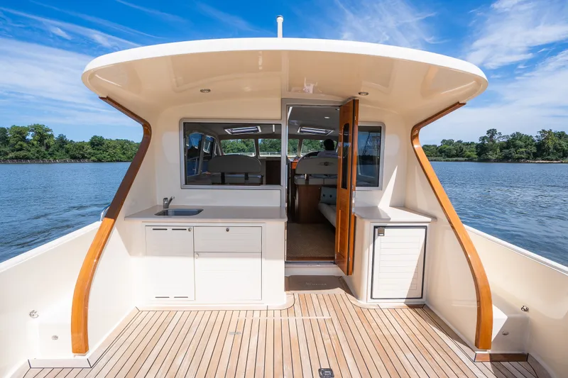 Slide: The Image of 2017 Palm Beach Motor Yachts PB42, elegant deck view with wooden accents on a serene waterway. - 9