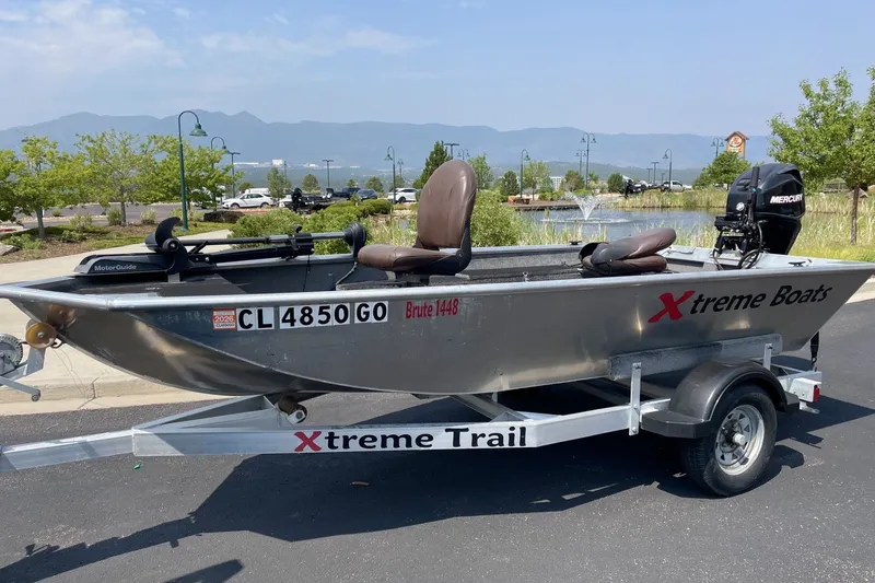 The Image of 2014 Extreme Boats Brute 1448T on trailer, parked near a scenic pond with mountains. - 1