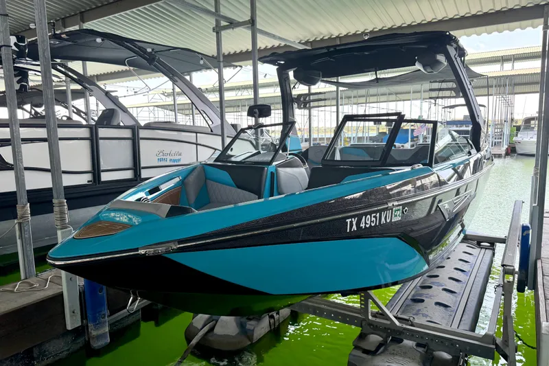 Slide: The Image of 2023 Tige Z3 boat in vibrant blue and black, docked in a marina. - 24