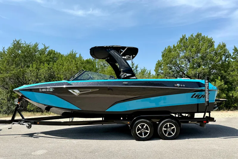 Slide: The Image of 2023 Tige Z3 boat on trailer, blue and black design, parked outdoors. - 8