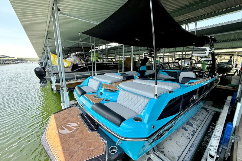 Slide: The Image of 2023 Tige Z3 boat in vibrant blue, docked under a covered marina. - 25