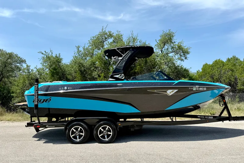 Slide: The Image of 2023 Tige Z3 boat on trailer, vibrant blue and black design, parked outdoors. - 12