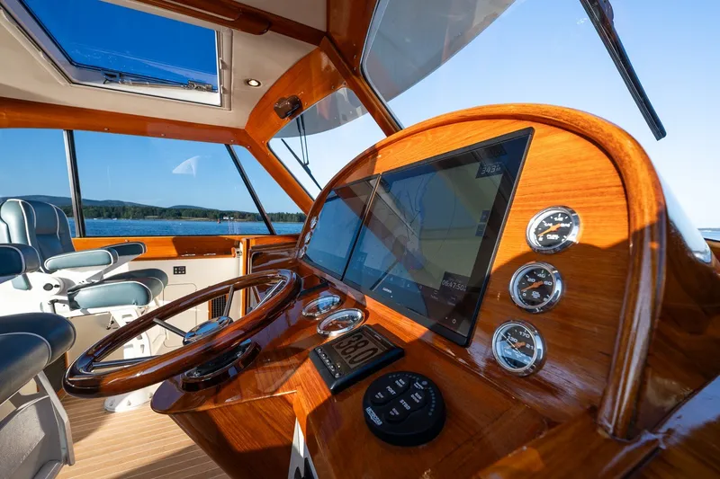 Slide: The Image of Helm of 2020 Hinckley Picnic Boat 40 with modern navigation instruments and luxurious wood finish. - 20