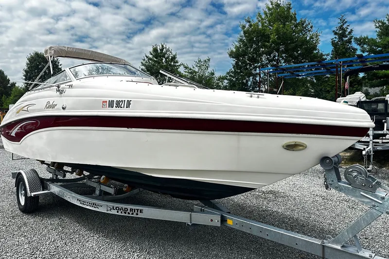 The Image of 2001 Rinker 232 Captiva Bowrider on trailer, parked outdoors under cloudy sky. - 0