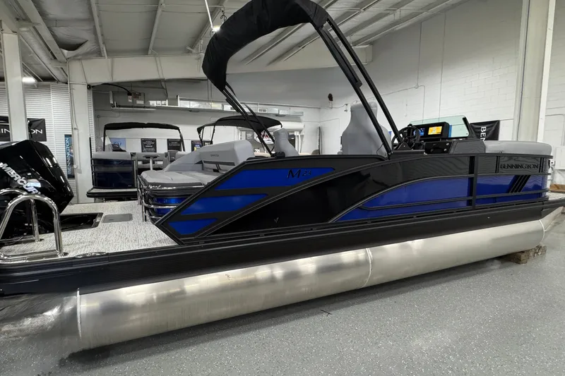Slide: The Image of 2026 Bennington 23 M Center Swingback pontoon boat in showroom, featuring sleek design and modern amenities. - 24