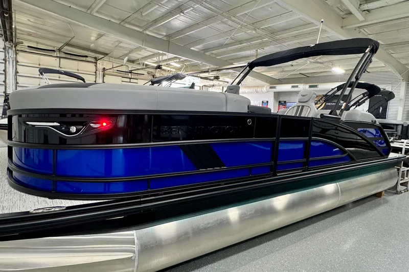 Slide: The Image of 2026 Bennington 23 M Center Swingback pontoon boat in showroom, featuring sleek blue and black design. - 21