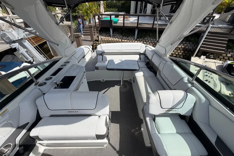 Slide: The Image of 2017 Formula 290 Bowrider interior with white seating and table, docked by a wooden deck. - 10
