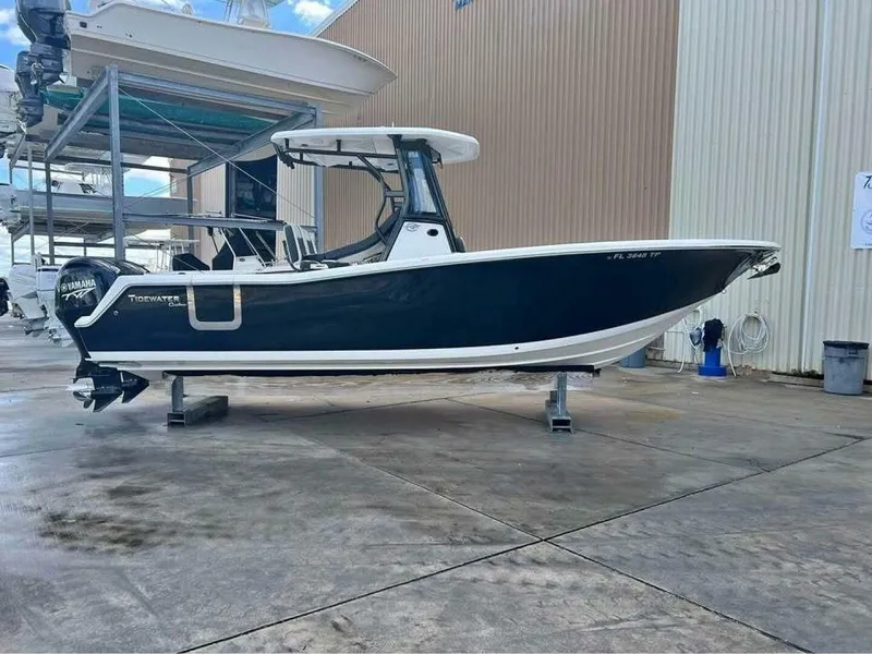 Slide: The Image of 2023 Tidewater 256 CC Adventure with a blue hull, on a dry dock, featuring a hardtop and outboard motor. - 14