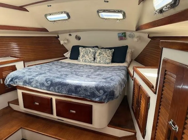 Slide: The Image of The image shows a cozy cabin with a double bed, wood accents, and porthole windows. - 31