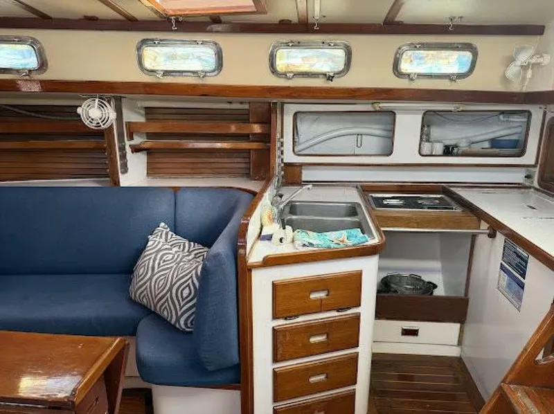 Slide: The Image of Interior of a 1989 Morgan 440 with blue couch, wooden furnishings, and a small kitchen area. - 30