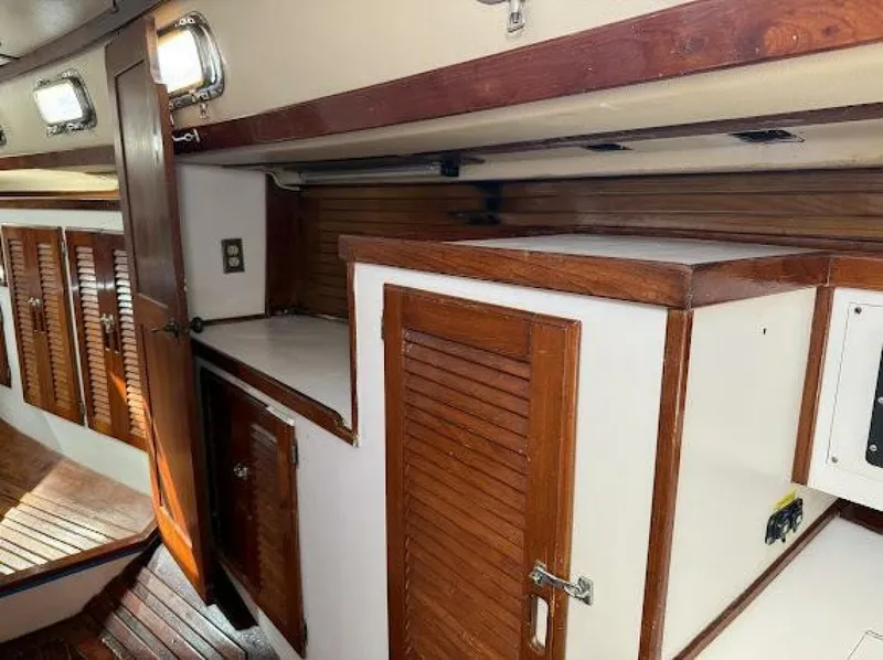 Slide: The Image of Interior of a sailboat with wooden doors and trim, white walls, and overhead lights. - 38