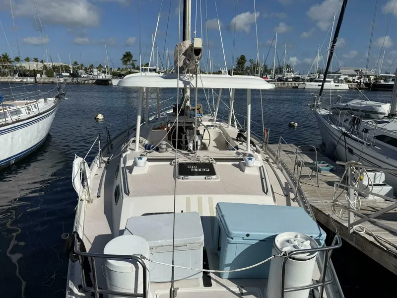 Slide: The Image of A 1989 Morgan 440 sailboat docked in a marina. It features a spacious deck and is surrounded by other boats. - 0
