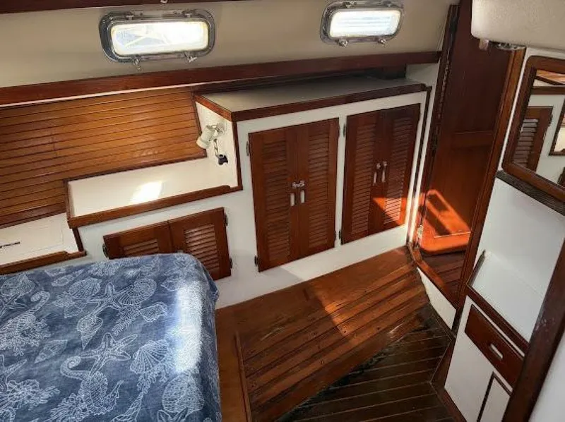 Slide: The Image of Interior of a 1989 Morgan 440 with wooden floors and cabinets, a bed, and windows. - 26
