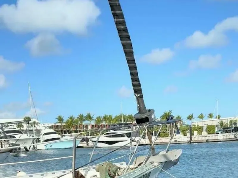 Slide: The Image of A sailboat is docked in a harbor, surrounded by other yachts and palm trees in the background. - 3