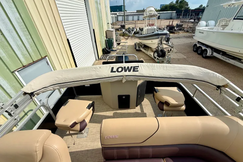 Slide: The Image of 2017 Lowe SF 214 Sport Fish pontoon boat with beige seating and canopy in a storage area. - 6