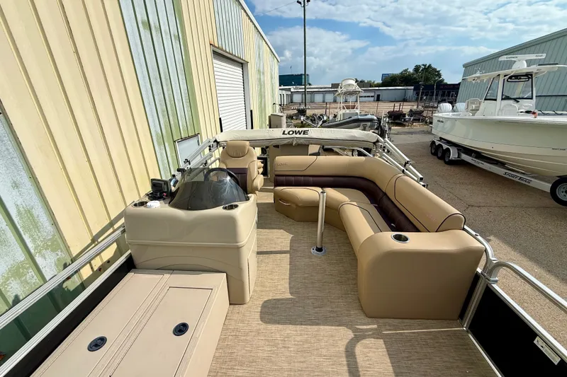 Slide: The Image of 2017 Lowe SF 214 Sport Fish pontoon boat with beige seating and helm, docked outdoors. - 5