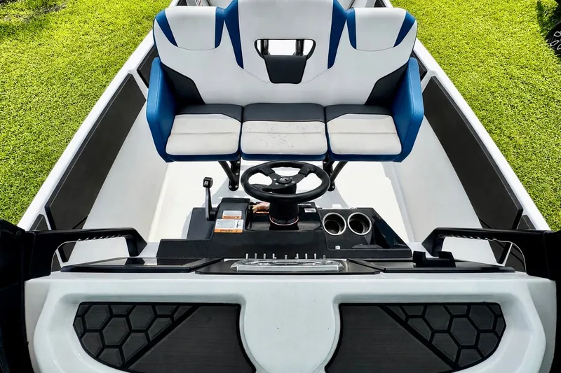 Slide: The Image of 2022 Scarab 255 Open ID boat interior with blue and white seating, steering wheel, and cup holders. - 14