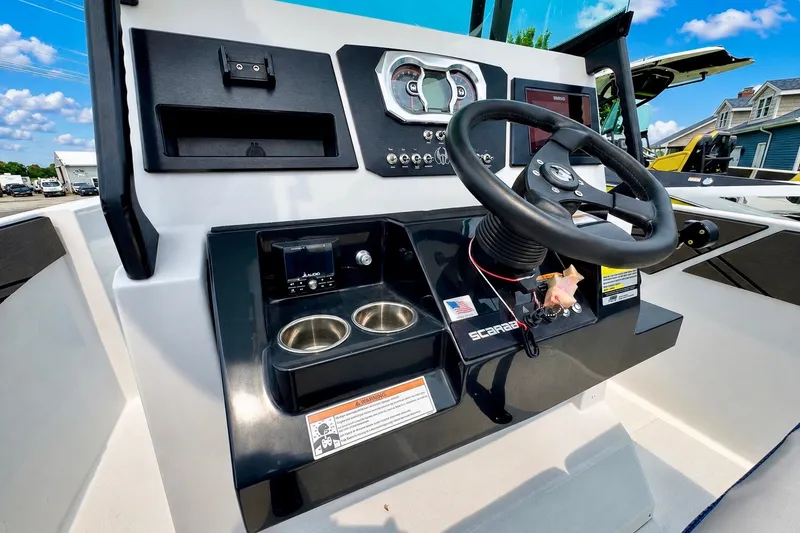 Slide: The Image of 2022 Scarab 255 Open ID boat dashboard with steering wheel and controls under a clear blue sky. - 16