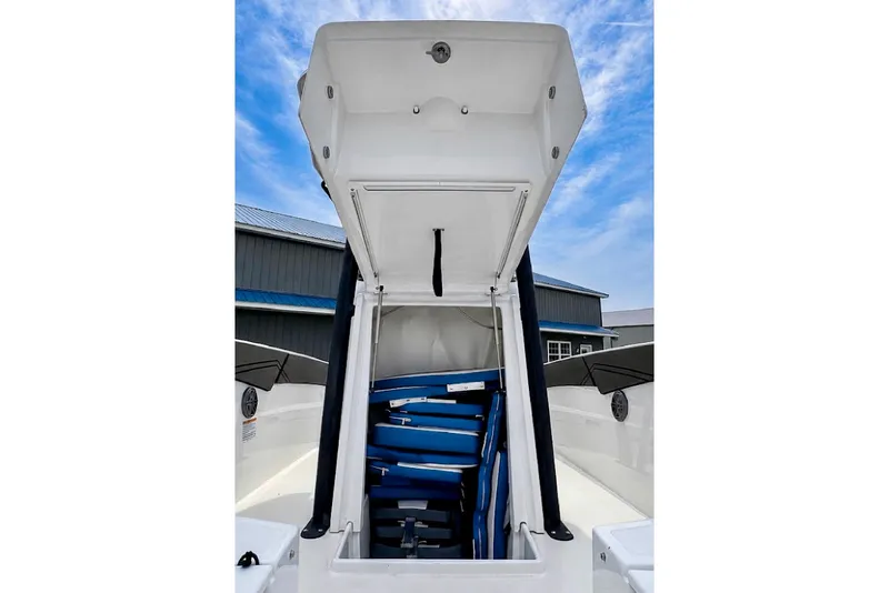 Slide: The Image of 2022 Scarab 255 Open ID boat storage compartment with blue cushions under a clear sky. - 17
