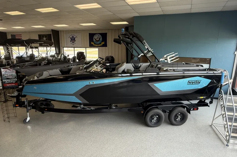 Slide: The Image of 2026 Heyday WTSurf boat in showroom, featuring sleek black and blue design. - 2