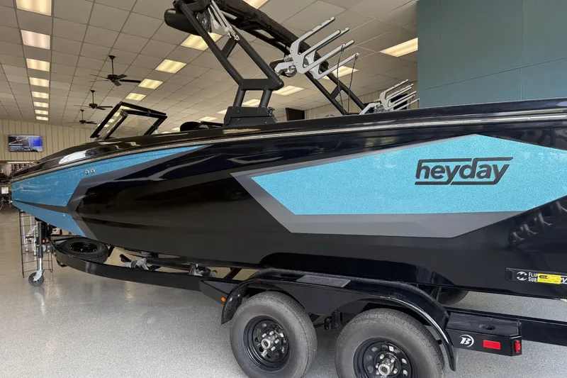 Slide: The Image of 2026 Heyday WTSurf boat in showroom, featuring sleek black and blue design. - 1