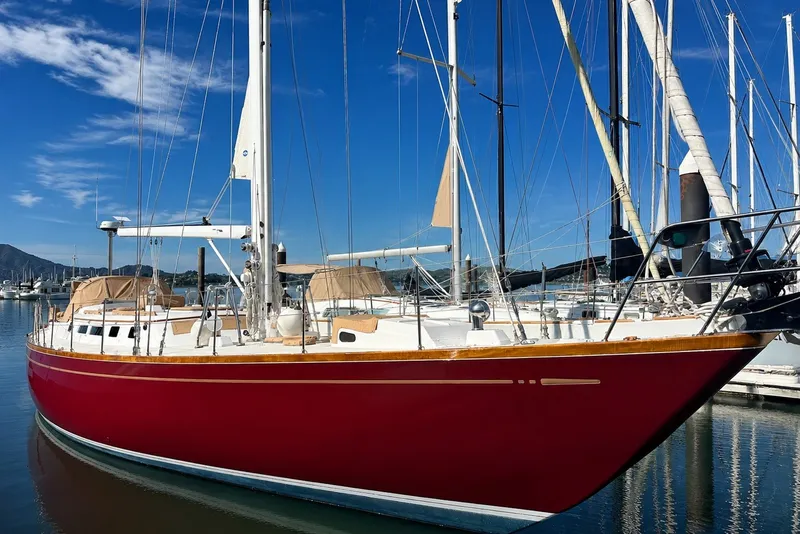 Slide: The Image of Red 1989 Mason 54 sailboat docked in a marina under a clear blue sky. - 3