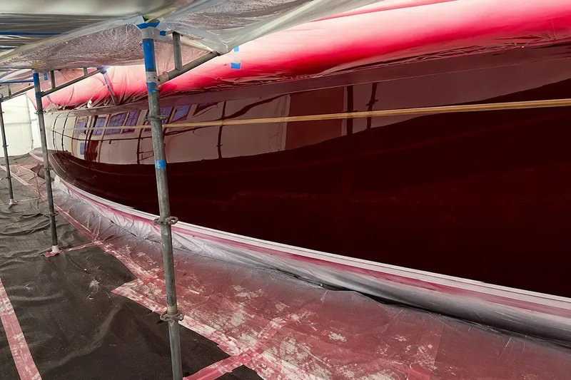 Slide: The Image of 1989 Mason 54 yacht under restoration, featuring a glossy red hull and scaffolding. - 9