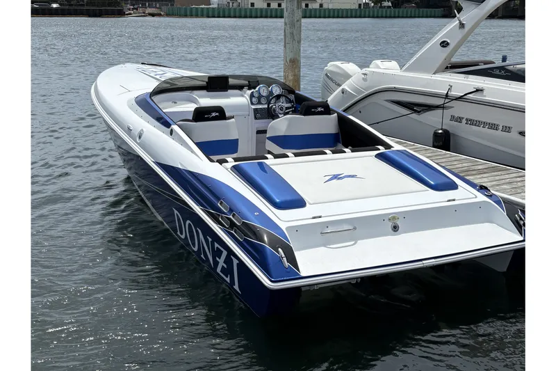 Slide: The Image of 2009 Donzi 27 ZR speedboat docked, featuring sleek blue and white design. - 2