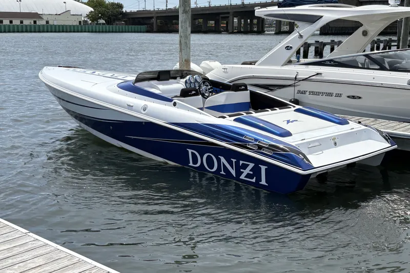 The Image of 2009 Donzi 27 ZR speedboat docked on calm water, featuring sleek blue and white design. - 1