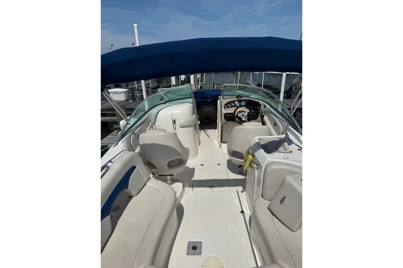 Slide: The Image of 2003 CHAPPARRAL 260 SSI boat interior with seating and steering wheel, docked under blue canopy. - 4