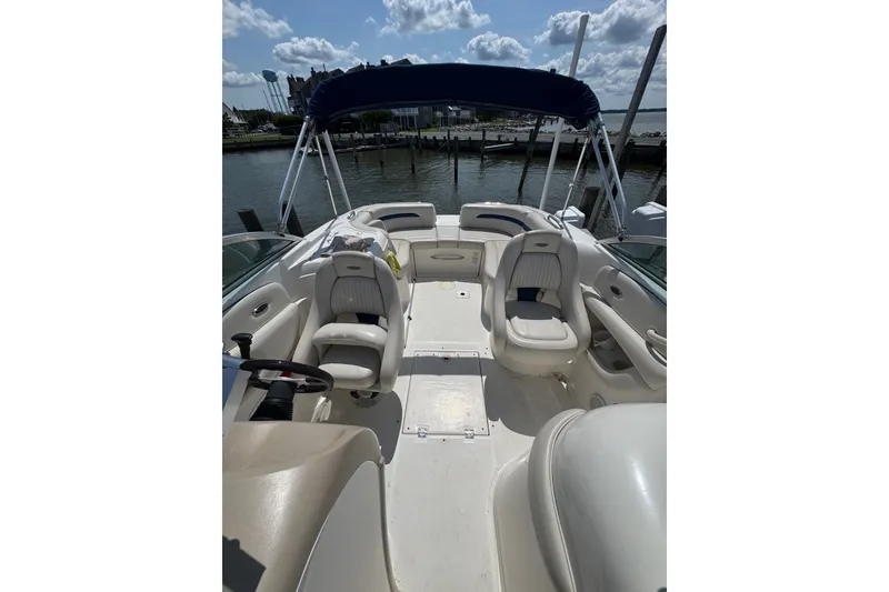 Slide: The Image of 2003 CHAPPARRAL 260 SSI boat interior with seating, steering wheel, and canopy under a sunny sky. - 3