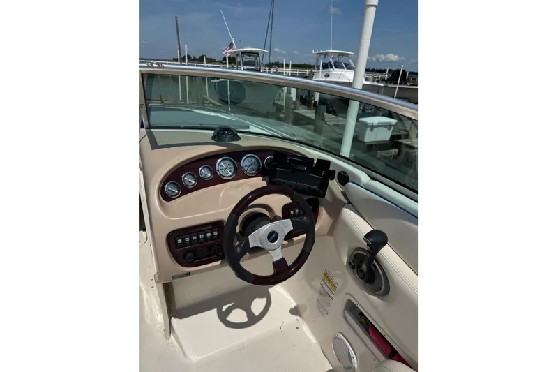 Slide: The Image of 2003 CHAPPARRAL 260 SSI boat dashboard with steering wheel and gauges in marina setting. - 5