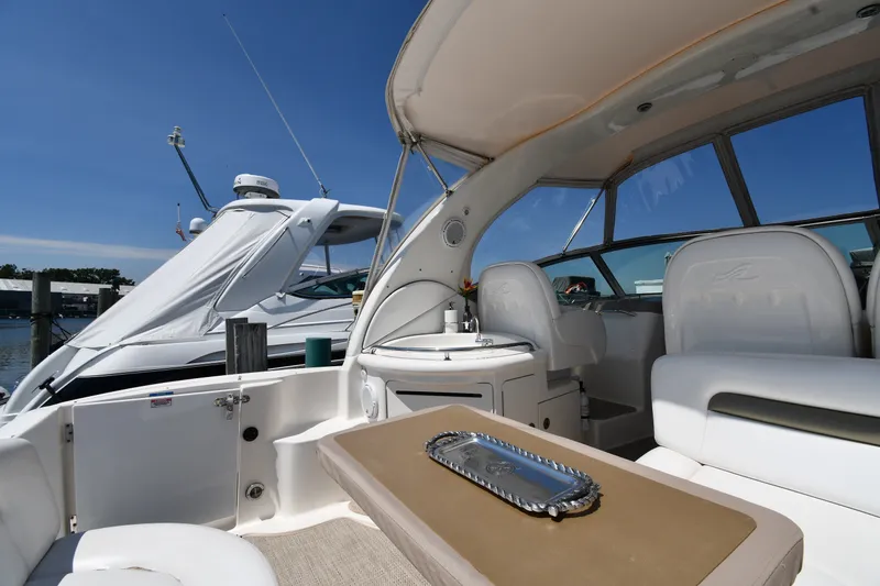 Slide: The Image of 2007 Sea Ray 340 Sundancer yacht interior with seating and table, docked under clear blue sky. - 18