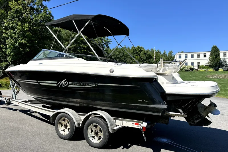 Slide: The Image of 2007 Monterey 234FSX boat on trailer, black and white design, parked outdoors under clear blue sky. - 2