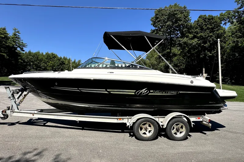 The Image of 2007 Monterey 234FSX boat on trailer, black and white, parked outdoors. - 0