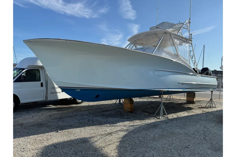 Slide: The Image of 2007 Outerbanks Express boat on stands, blue hull, clear sky background. - 0