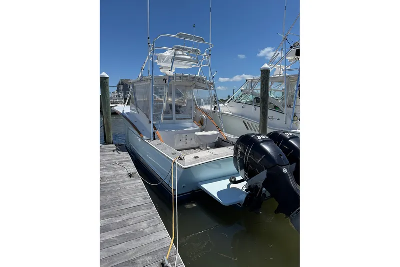 The Image of 2007 Outerbanks Express boat docked with twin engines under clear blue sky. - 5