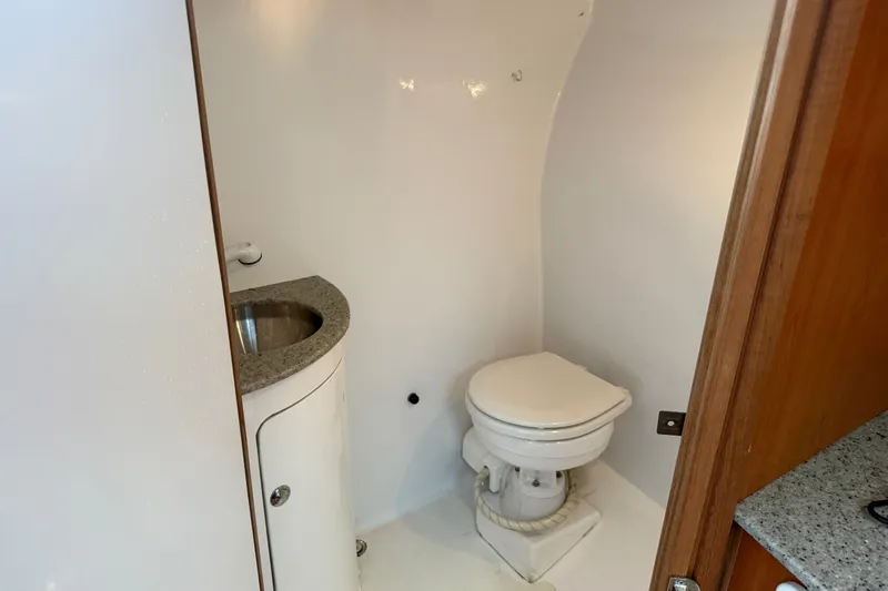 Slide: The Image of Compact bathroom in a 2007 Outerbanks Express boat, featuring a toilet and sink. - 24