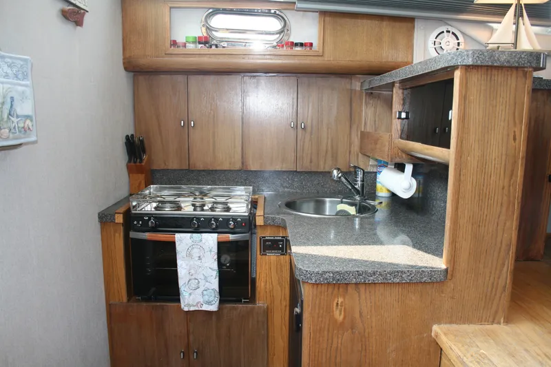 Slide: The Image of 1989 Silverton 34 Convertible yacht kitchen with stove, sink, and wooden cabinetry. - 17